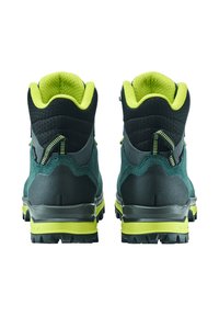 Scarpe da trekking verde scuro con dettagli neri, caratterizzate da una tomaia testurizzata, colletto imbottito e suole gialle vivaci. La vista posteriore mostra i dettagli del design.