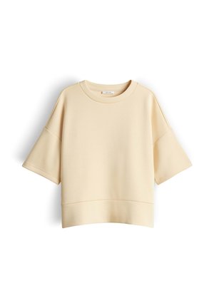 Beige oversized korte mouw sweatshirt met verlaagde schouders en ronde halslijn, weergegeven op een witte achtergrond.