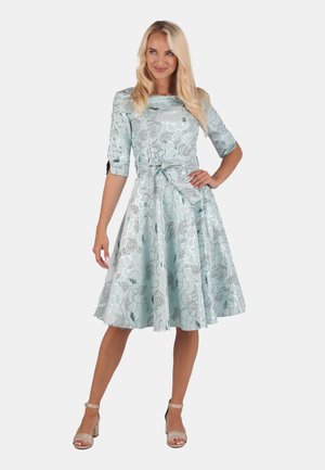 Light blue dress with a floral design, three-quarter sleeves, a cinched waist, and a flowing skirt. Paired with metallic strappy heels.