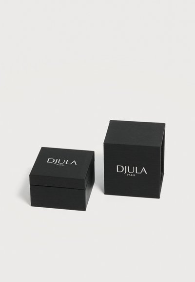 Deux boîtes à bijoux carrées noires avec logos blancs « DJULA PARIS » sur un fond clair uni, une fermée et une ouverte.