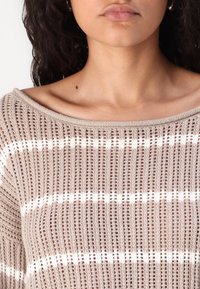 Hellbrauner Strickpullover mit weitem Ausschnitt, der vertikale Streifen und ein strukturiertes Muster aufweist. Das Material wirkt leicht und luftig.