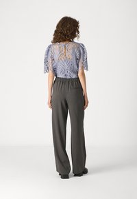 Lavender lace blouse with puff sleeves, featuring intricate patterns and a keyhole back, paired with charcoal pinstripe wide-leg trousers.