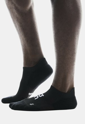 Chaussettes noires mi-mollet avec un ajustement serré, arborant une surface texturée et un logo blanc sur le côté. Un tissu lisse améliore le confort lors du port.