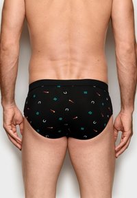 Sorte trusser med et mønster af forskellige farverige symboler, herunder kløver og tændstikker, med en blød elastisk talje.