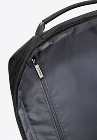 Borsa in tessuto nero con un interno liscio e un compartimento con zip. Dotata di un tirante della zip testurizzato e di una maniglia robusta.
