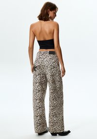 Pantaloni palazzo in stampa leopardata realizzati in tessuto testurizzato, con vita alta e dettagli neri sulle tasche posteriori.