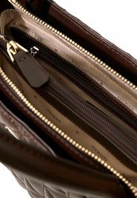 Sac à main en cuir matelassé marron avec plusieurs compartiments zippés, quincaillerie dorée et doublure intérieure beige présentant un motif géométrique.