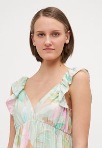Φόρεμα με floral σχέδιο σε παστέλ αποχρώσεις, με V-neck και φρουριστές τιράντες. Ελαφρύ ύφασμα με μαζεμένη λεπτομέρεια στη μέση.