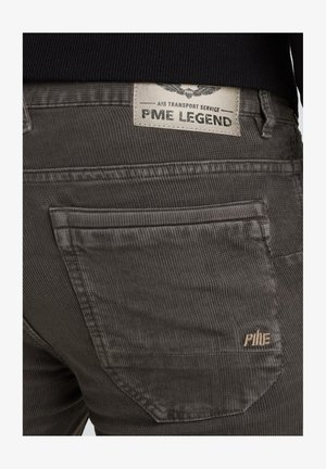 Grau gestreifte Cordhosen mit einem gewebten Label auf der Rückseite, das "PME LEGEND" liest. Die Textur ist gerippt mit einer glatten Oberfläche und subtilen Nähdetails.