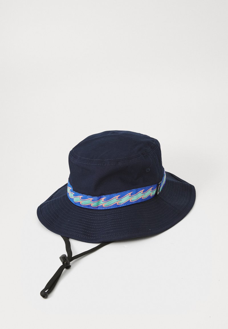 Námořnická modrá kbelíková čepice vyrobená z bavlny, s barevným pásem s vzorem vln a nastavitelným podbradním páskem.