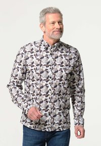 Lange mouw blouse met een bloemenpatroon in bruin, zwart en crème op een lichte achtergrond, gemaakt van lichte stof.