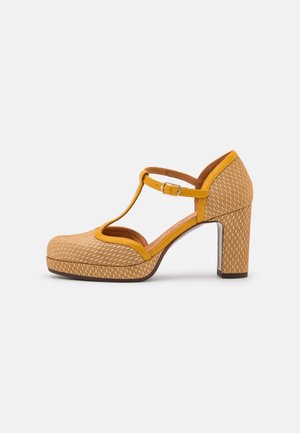 Chaussure à talon haut à bride en T à motif marron clair avec talon bloc, garniture et boucle jaunes, présentée en profil latéral sur fond blanc.