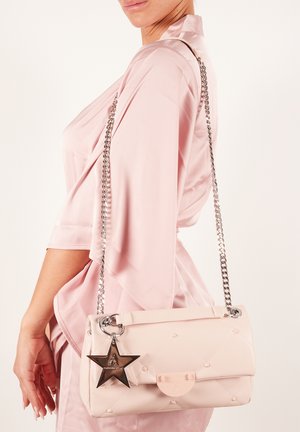 Jasnoróżowa pikowana torebka na łańcuszku w kolorze srebrnym, zdobiona charmsami w kształcie gwiazdy i wykonana z gładkiego materiału. Udekorowana małymi wytłaczanymi detalami.