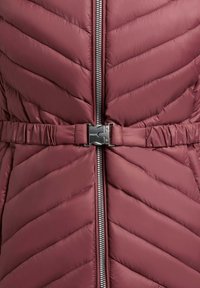 Tumepunane tikitud jope diagonaalse õmblusega, keskel hõbedane tõmblukk ja sobiv vöö metallist pandlaga.