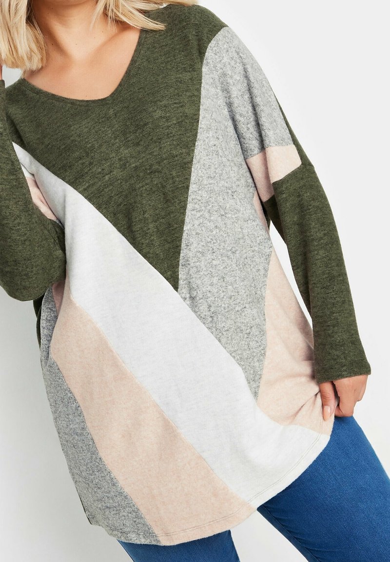 Pull vert surdimensionné avec un décolleté en V, des manches longues, et un design en blocs de couleurs avec des sections grises, roses et blanches. Tissu doux et texturé.