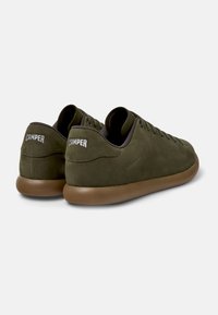 Sneaker in suede verde oliva con design low-top, caratterizzati da suola in gomma marrone e logo "CAMPER" sul tallone. Dettaglio classico dei lacci.