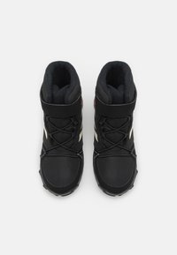 Botas altas negras con una superficie texturizada, cordones flexibles, cuello acolchado y acentos en blanco en los laterales.