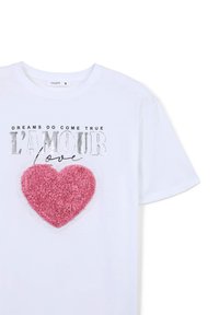T-shirt bianco con un design di cuore rosa testurizzato e forme a strati simili a fiori. Testo argentato sopra che recita "I SOGNI DIVENTANO REALTÀ" e "L'AMOUR amore."