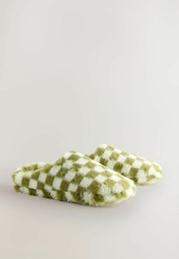 Fuzzy slippers featuring a green and white checkered pattern. Soft texture with a rounded toe design and an open back style.