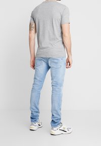 Grå kortärmad t-shirt matchad med ljusblå jeans och gråa och vita sneakers. Outfitten har en avslappnad, figurnära design.