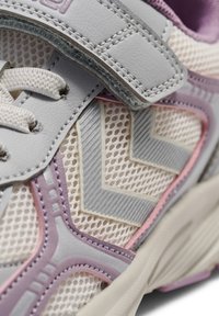 Lichtgrijze sportschoen met een bovenwerk van mesh, voorzien van lavendel- en roze accenten, textuurpatronen en een klittenbandsluiting.