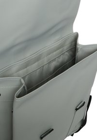 Wnętrze szarej syntetycznej torby z wieloma przegrodami; gładka tekstura, czarne akcenty hardware'owe i wzmocnione detale szwów.