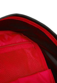 Interior de una bolsa de tela roja con un bolsillo con cremallera y detalles de malla, con un forro negro suave. Múltiples compartimentos para una mejor organización.