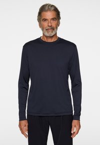 Mörkblå långärmad skjorta, rundad halsringning, gjord av mjukt tyg. Har en liten logotyp på bröstet. Mjuk textur, avslappnad passform, lätt design.