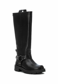 Bota de cuero negra hasta la rodilla con punta redondeada, detalle de correa en el tobillo, hebillas plateadas y suela de goma texturizada para tracción.