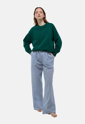 Sweatshirt en coton vert avec des épaules tombantes associé à un pantalon large rayé bleu clair. Les deux pièces ont une coupe décontractée et une texture douce.