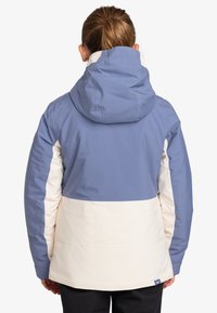 Damen Kapuzenjacke mit einem hellblauen oberen Abschnitt, einem cremefarbenen Mittelabschnitt und dunkellblauen Akzenten. Hergestellt aus glattem, strapazierfähigem Material.