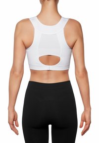 Weißer Sport-BH mit Racerback-Design, ausgestattet mit einem Netzpaneel und einem runden Ausschnitt im Rücken; kombiniert mit schwarzen Leggings.