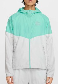 Lekka kurtka z miętowo-zieloną górą i białym dołem. Wzór z kapturem, z zamkiem błyskawicznym i bocznymi kieszeniami. Logo Nike na piersi.