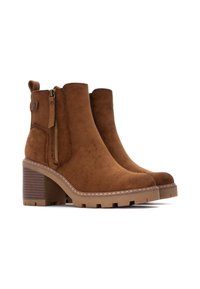 Stivaletti in suede marrone con punta tonda, zip laterale e tacco spesso e rigato. Presentano una suola texturizzata e cuciture decorative.