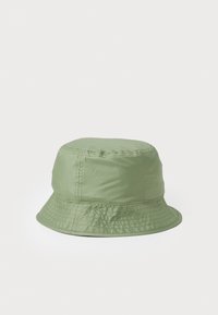 Groene bucket hat gemaakt van glad, waterafstotend materiaal. Beschikt over een brede, gestikte rand en een naadloze kroon. Eenvoudig ontwerp.