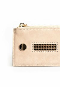 Lichtbeige leren portemonnee met een gouden rits, voorzien van een achtzijdige zwarte accent en een horizontaal gaasontwerp aan de voorkant.