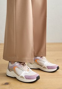 Baskets blanches, violettes et orange fabriquées en maille et en daim. Elles disposent d'un col rembourré, d'une semelle contrastée et de lacets bien visibles.