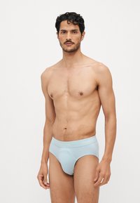 Svetele modre bombažne spodnje hlačke z mehkobnim pasom, ki nosi logotip "Calvin Klein", prilegajoča zasnova in gladka tekstura.