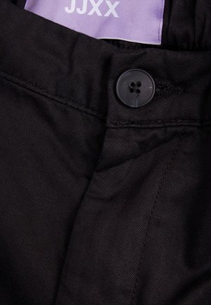 Schwarze Stoffhosen mit einem schwarzen Knopfverschluss, sichtbaren Nähdetails und einem lila Etikett mit der Aufschrift "JJXX."