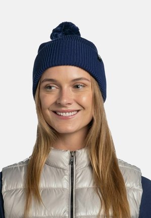 Navy knitted beanie with a ribbed texture and a pom-pom on top, paired with a silver puffer vest featuring a zip front.