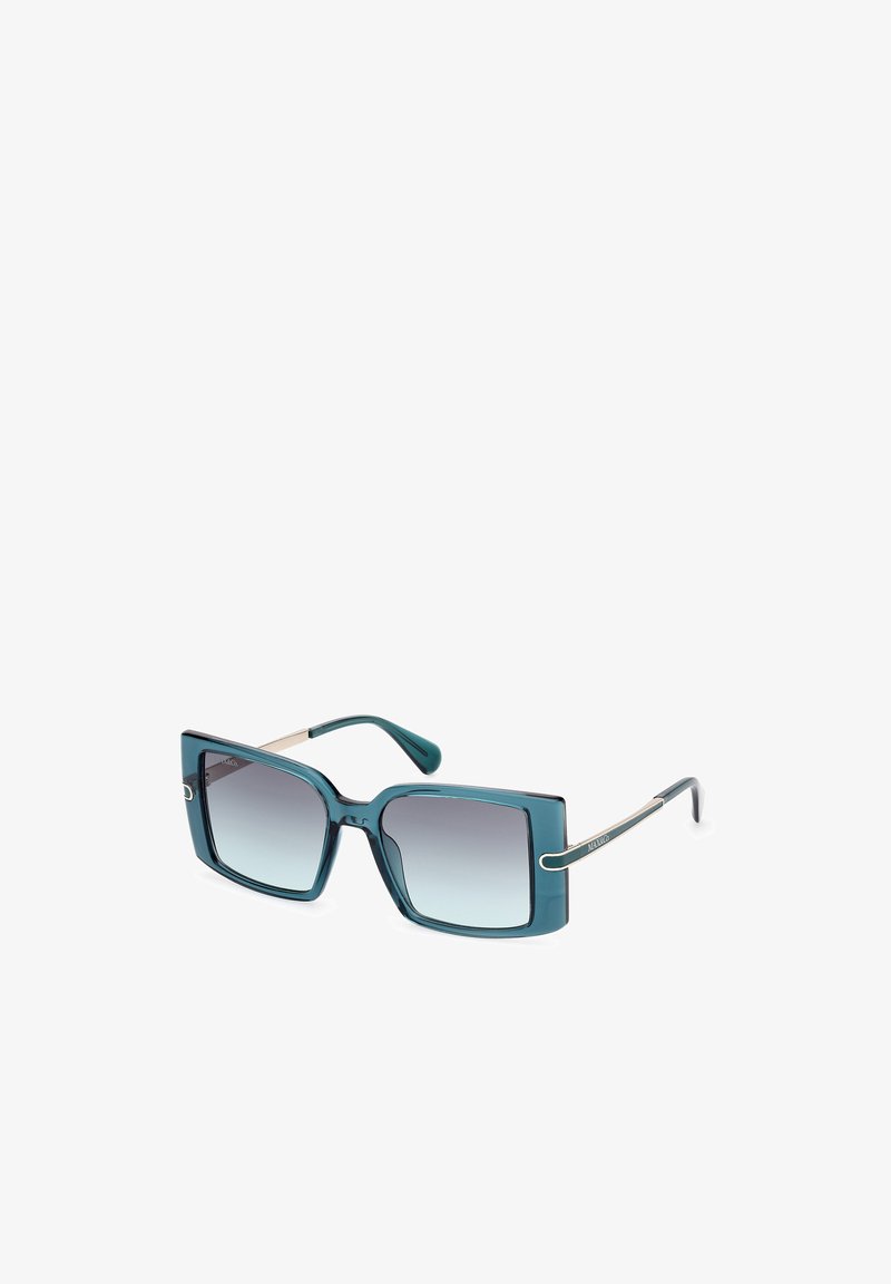 Occhiali da sole quadrati color teal con lenti sfumate. Sottili dettagli in metallo sulle astine. Montatura in plastica lucida con un audace design geometrico.