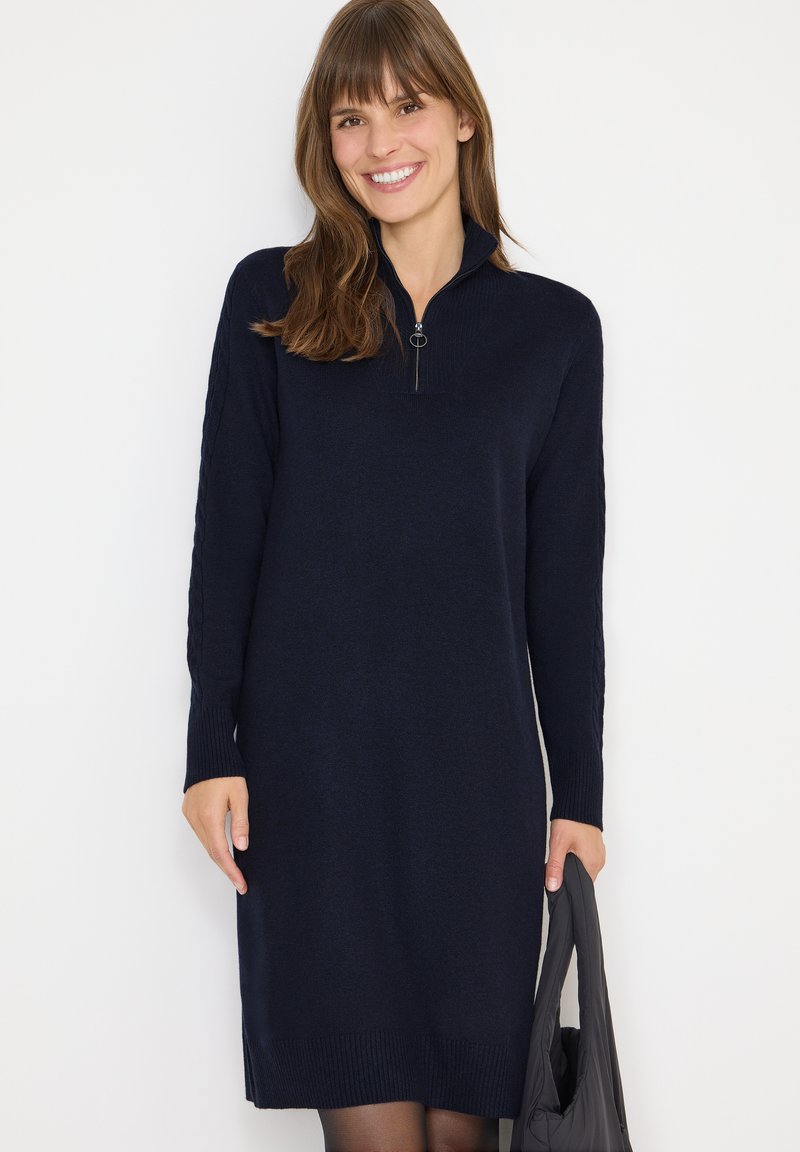 Abito in maglia navy con collo zip, polsini a costine e spacchi laterali. Tessuto a maglia con dettagli a treccia sulle maniche. Vestibilità accentuata.