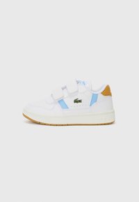 Baskets blanches avec des accents bleu et marron clair, double bandes Velcro, détails perforés et un logo brodé vert sur le côté.