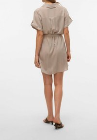 Abito corto a righe in beige chiaro con righe più scure, maniche corte, vita con cintura e vestibilità rilassata, con colletto e dettagli con bottoni.