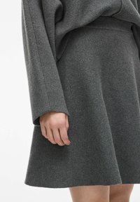 Šedý pletený top s dlouhým rukávem a sukně v kombinaci, s jemnou texturou a volným střihem, s viditelnými švy a rozšířeným designem sukně.