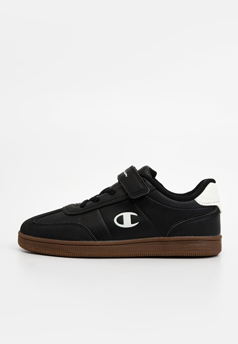 Baskets basses noires avec semelle marron, languette blanche au talon, bande velcro et logo Champion blanc sur le côté.
