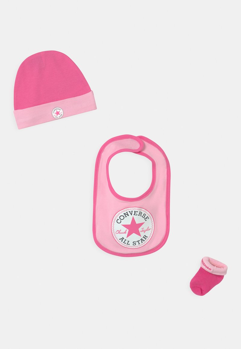Set za bebe od tri dijela uključuje ružičastu pletenu kapicu, ružičasti ubrus s bijelim zvjezdastim logotipom i odgovarajuće ružičaste čarape s manžetom.