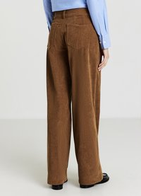 Braune Cordhose mit weitem Bein, ausgestattet mit vertikaler Rippenstruktur, zwei Gesäßtaschen und hoher Taille mit Gürtelösen.