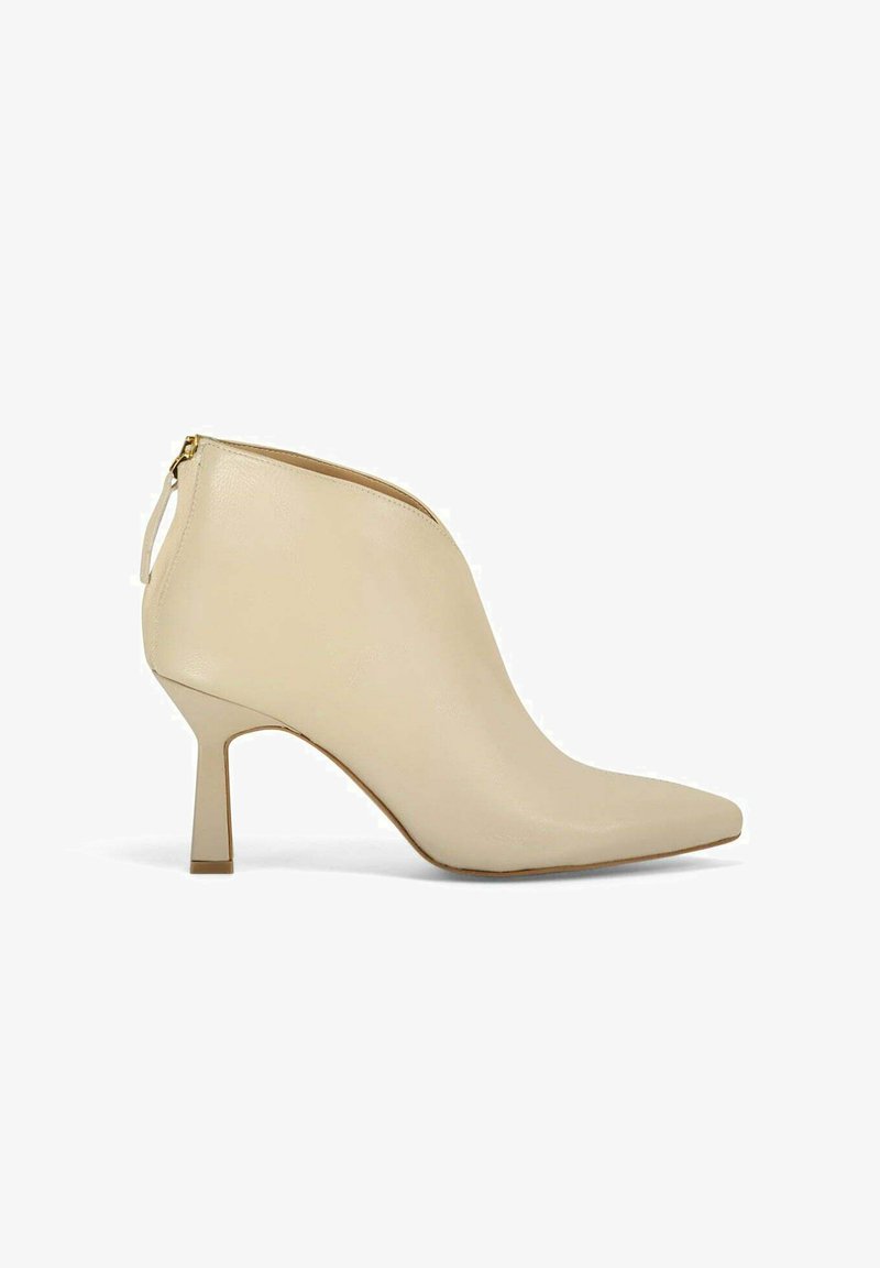 Bottines en cuir beige avec des orteils pointus, une silhouette élégante et un talon bloc de hauteur intermédiaire. Comprend une fermeture éclair dorée et une languette à l'arrière.