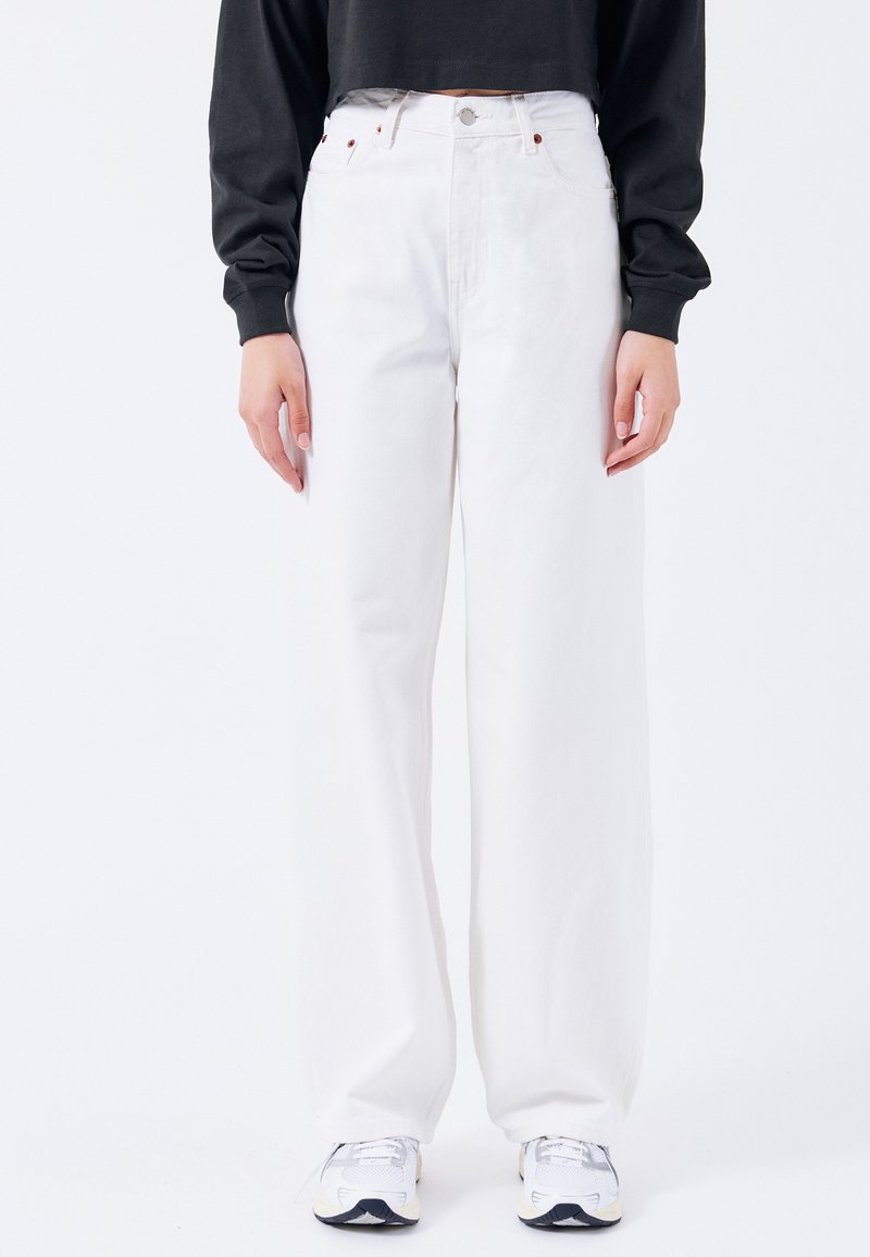 Pantalones vaqueros amplios blancos hechos de denim grueso, con una cintura alta, diseño de cinco bolsillos y discretos acentos de costura roja.